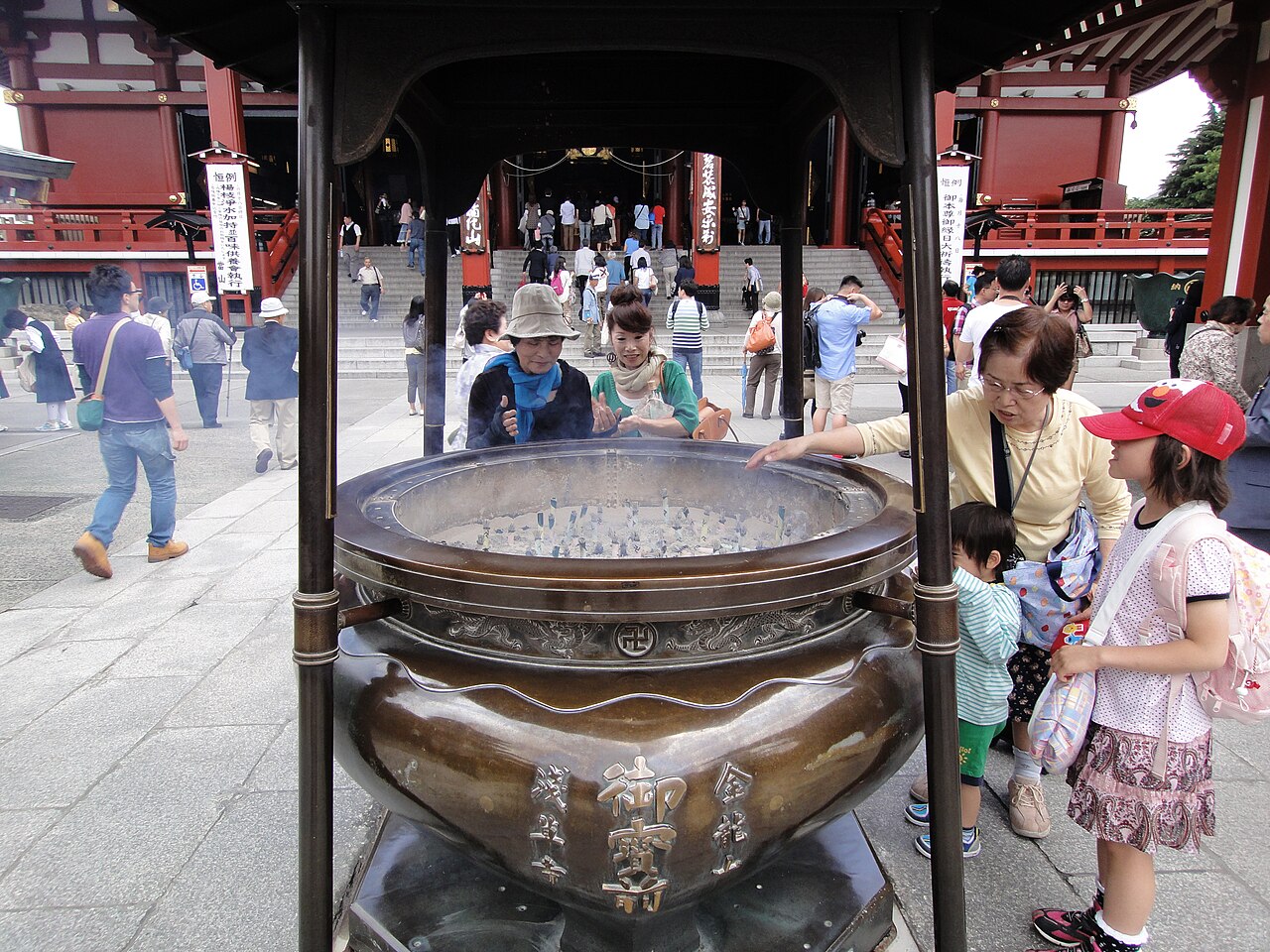 Visitors waft incense smoke over themselves at the jōkōro burner before the main hall of Sensō-ji