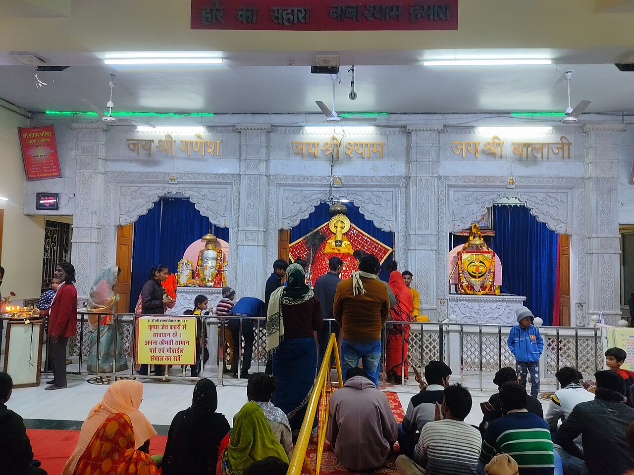 The white marble darshan hall of Shri Khatu Shyam Ji Temple, with the shish of Baba Shyam in shringar between the Ganesh and Balaji shrines