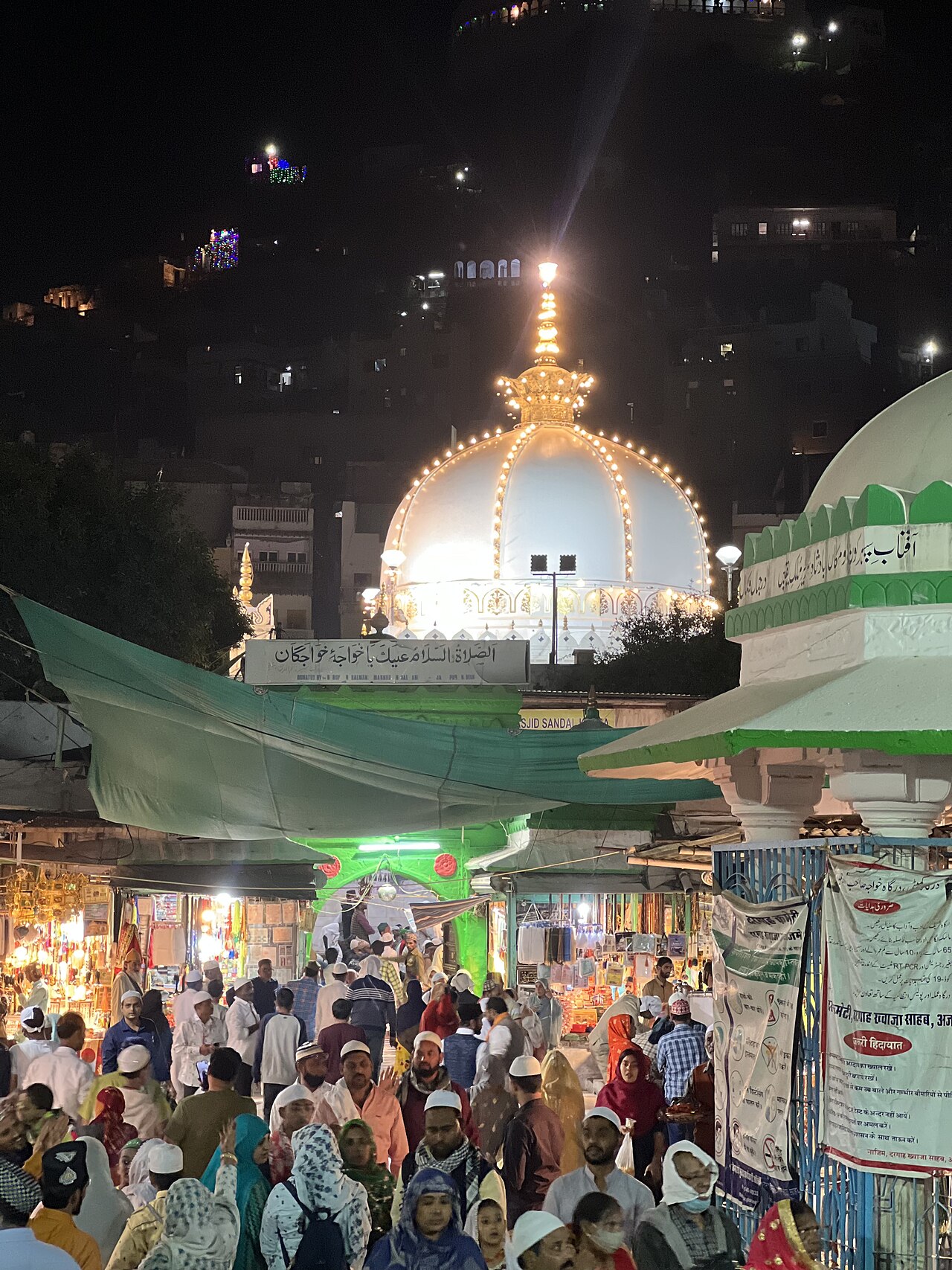 The illuminated white dome of the Ajmer Sharif Dargah rising over the crowded bazaar during the Urs
