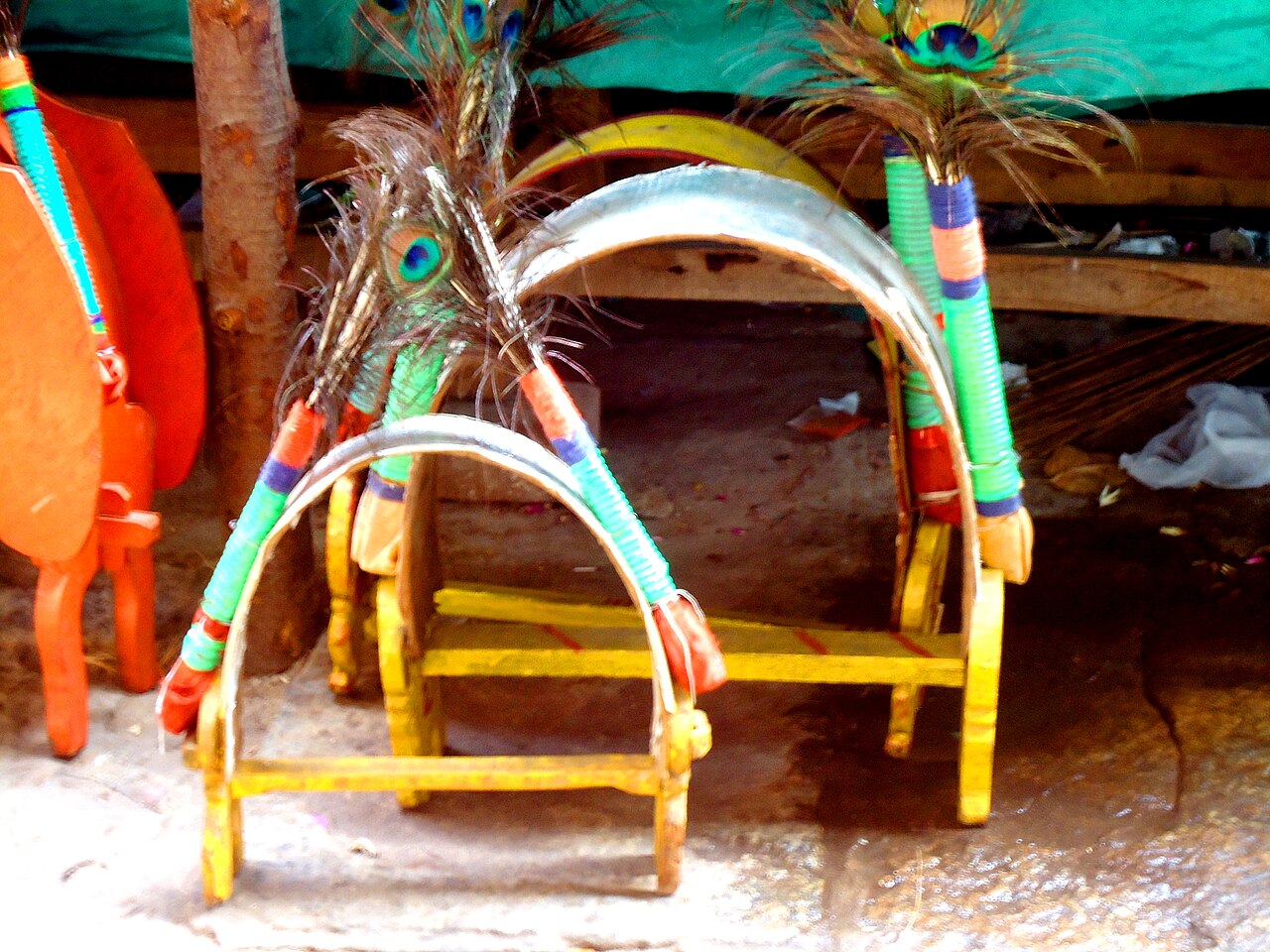 Peacock-feather kavadis, the arched shoulder burdens of Palani pilgrims, kept ready near the hill