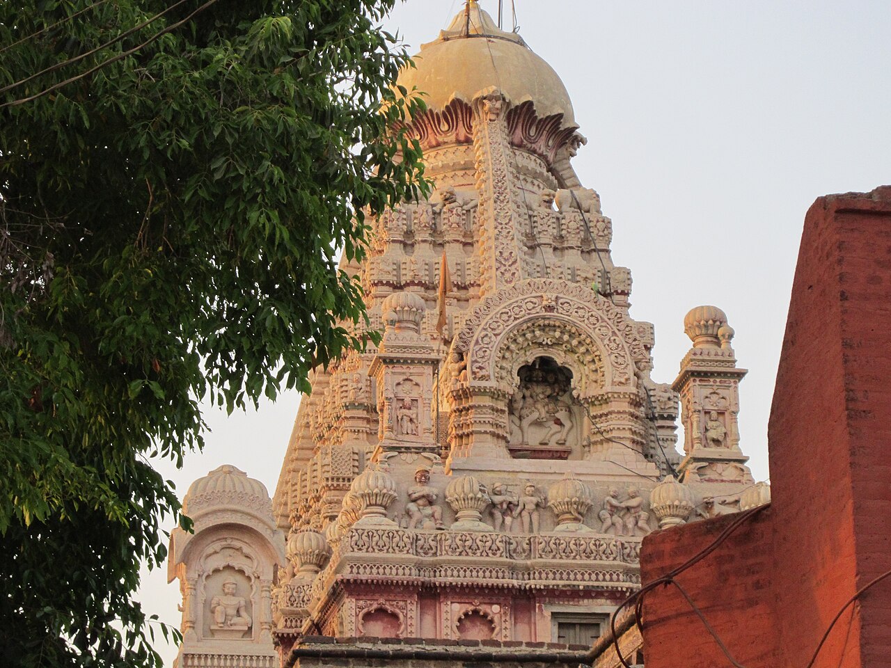 Carved figures and floral bands on the red stone shikhara of Grishneshwar temple at dusk