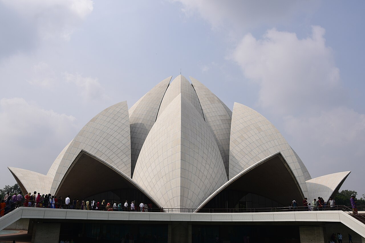 Visitors filing along the parapet beneath the white marble petals of the Lotus Temple