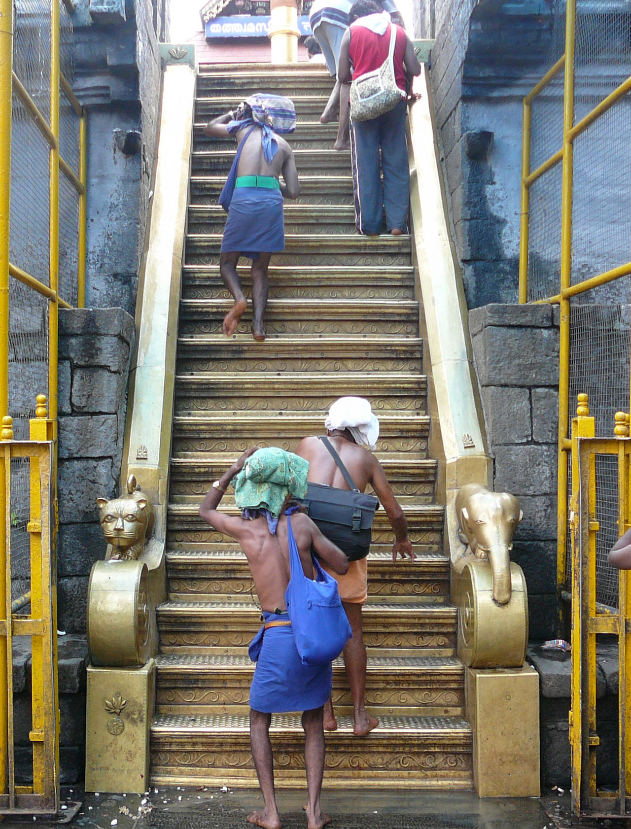 Pilgrims with irumudi bundles on their heads climbing the eighteen gold-clad sacred steps at Sabarimala