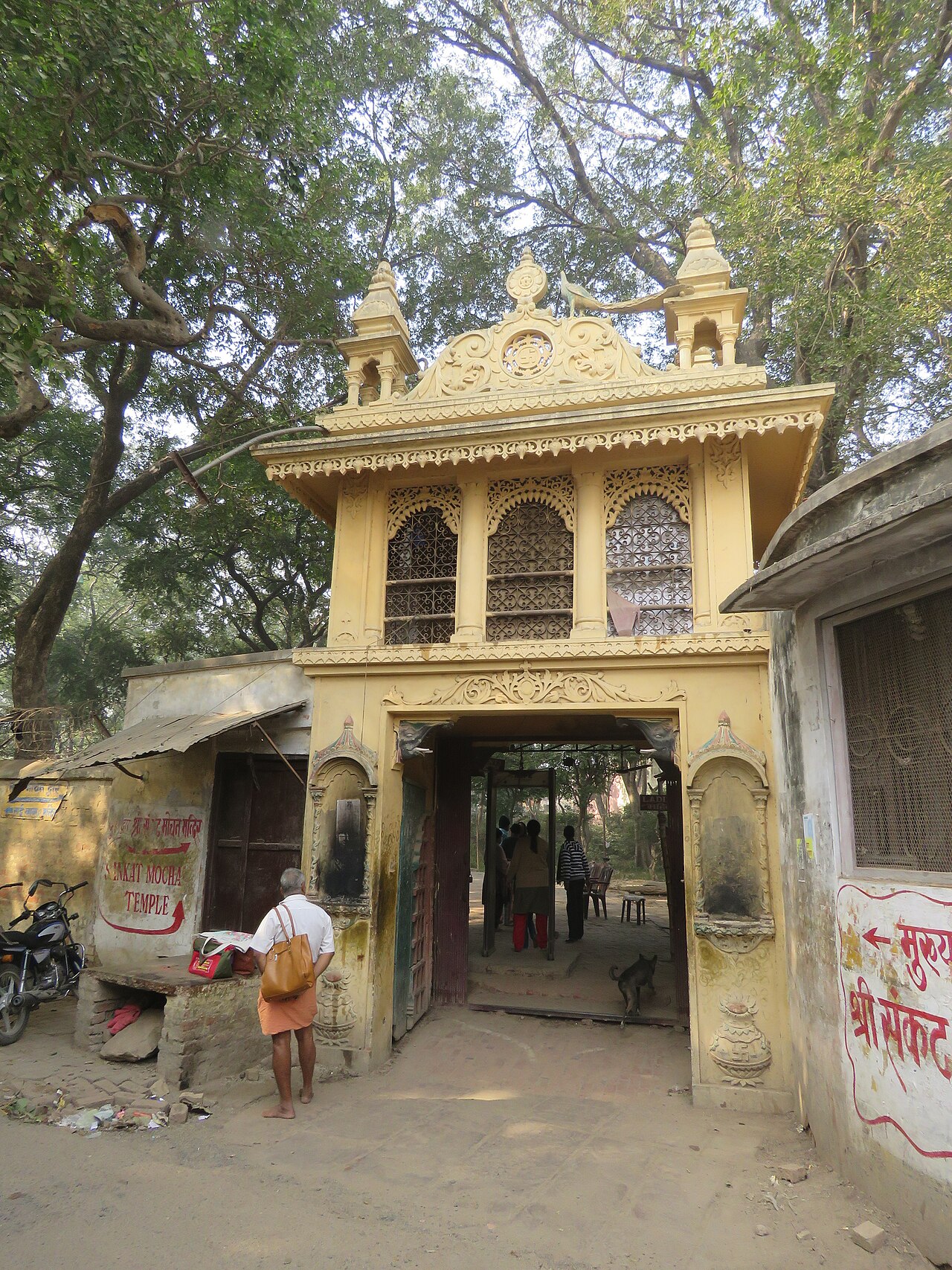 Devotees passing through the Temple's entrance gate as one of the resident monkeys crosses the threshold