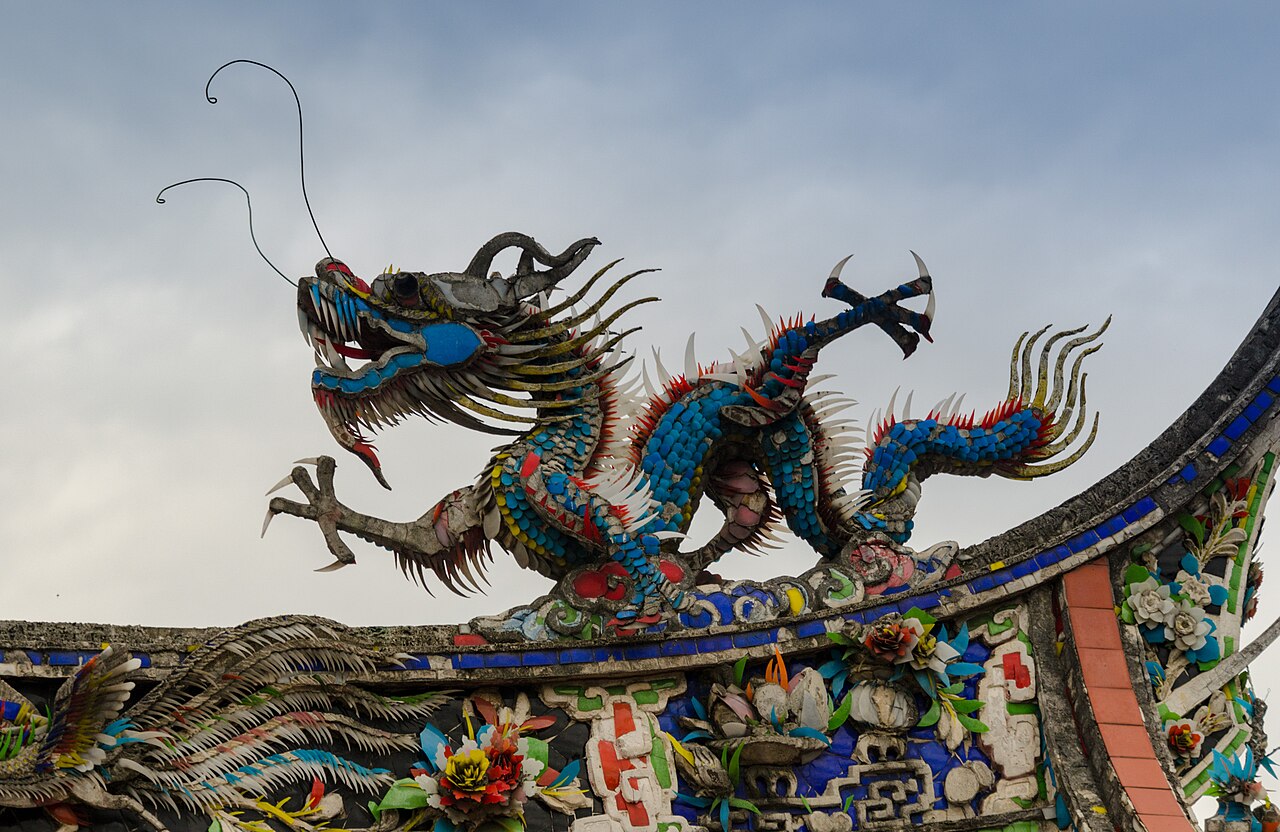 A blue cut-porcelain dragon cresting a swallowtail roof ridge at Bangka Lungshan Temple
