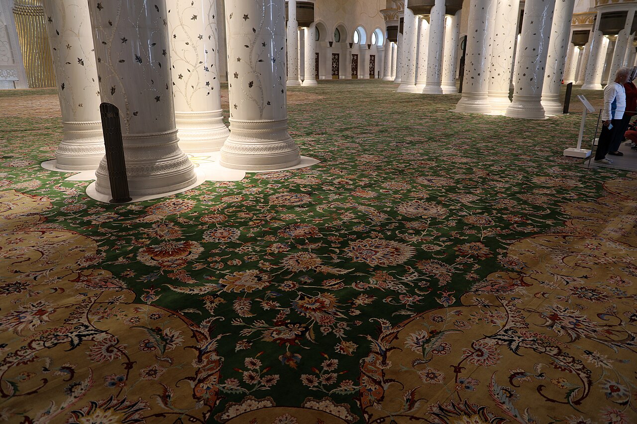 The world's largest hand-knotted carpet flowing around the marble columns of the main prayer hall