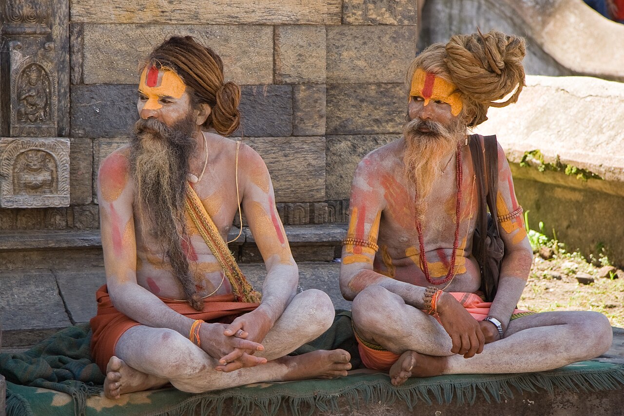 Two sadhus seated against carved stone in the Pashupatinath precinct, Kathmandu