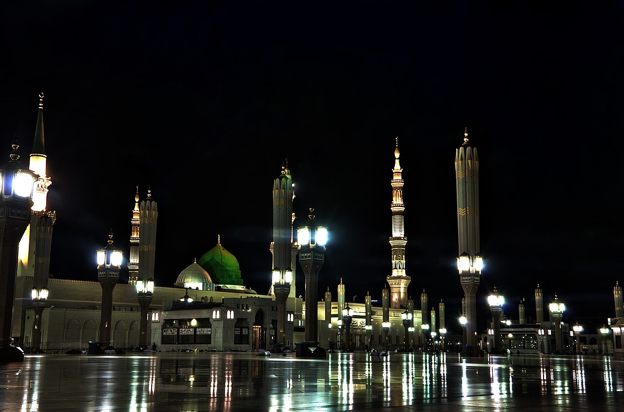 Al-Masjid an-Nabawi glowing at night, its minarets lit above the marble courts