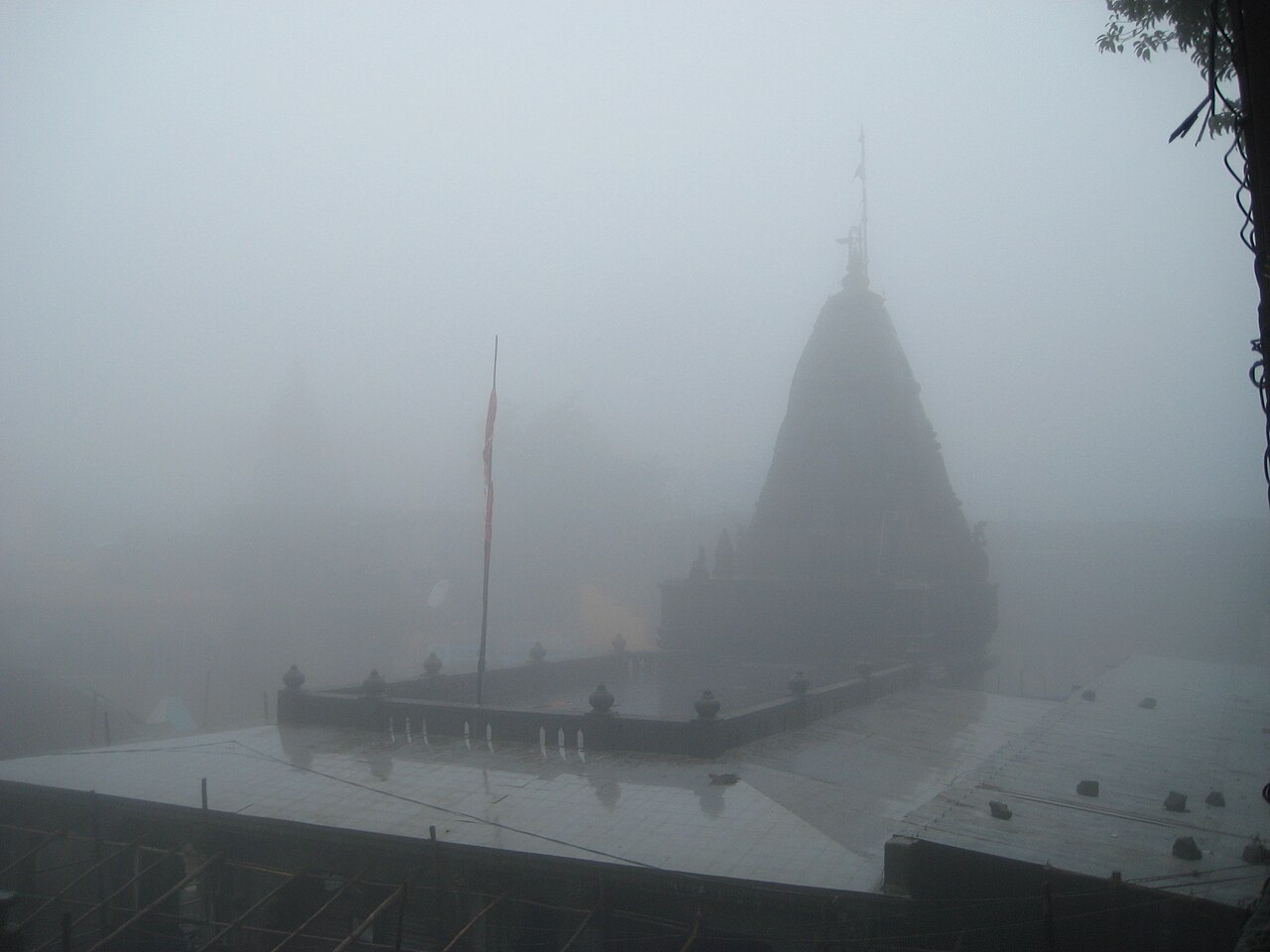 Bhimashankar temple and its saffron flag dissolving into monsoon mist on the Sahyadri crest