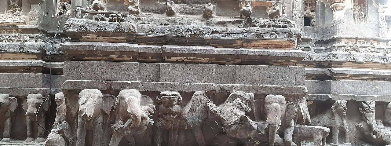 The frieze of stone elephants carved around the base of the Kailasa Temple, seeming to bear the shrine on their backs