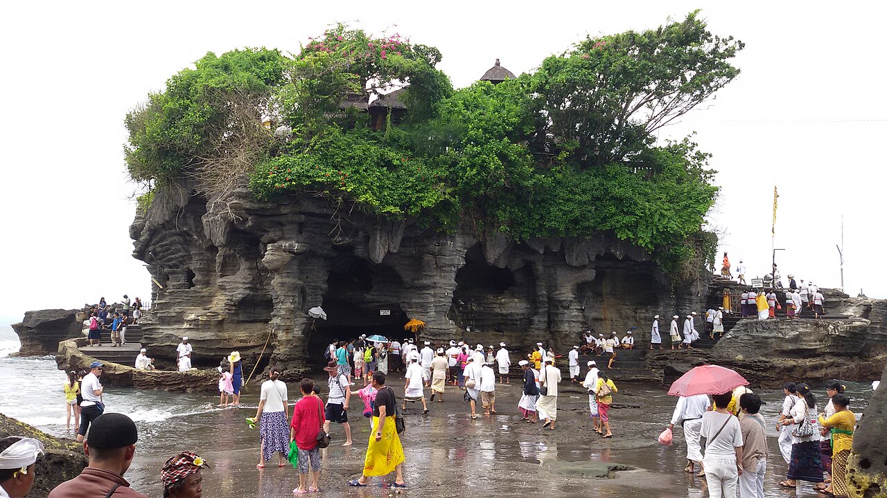 Pemedek in temple dress cross the wet causeway at low tide during the odalan at Pura Tanah Lot