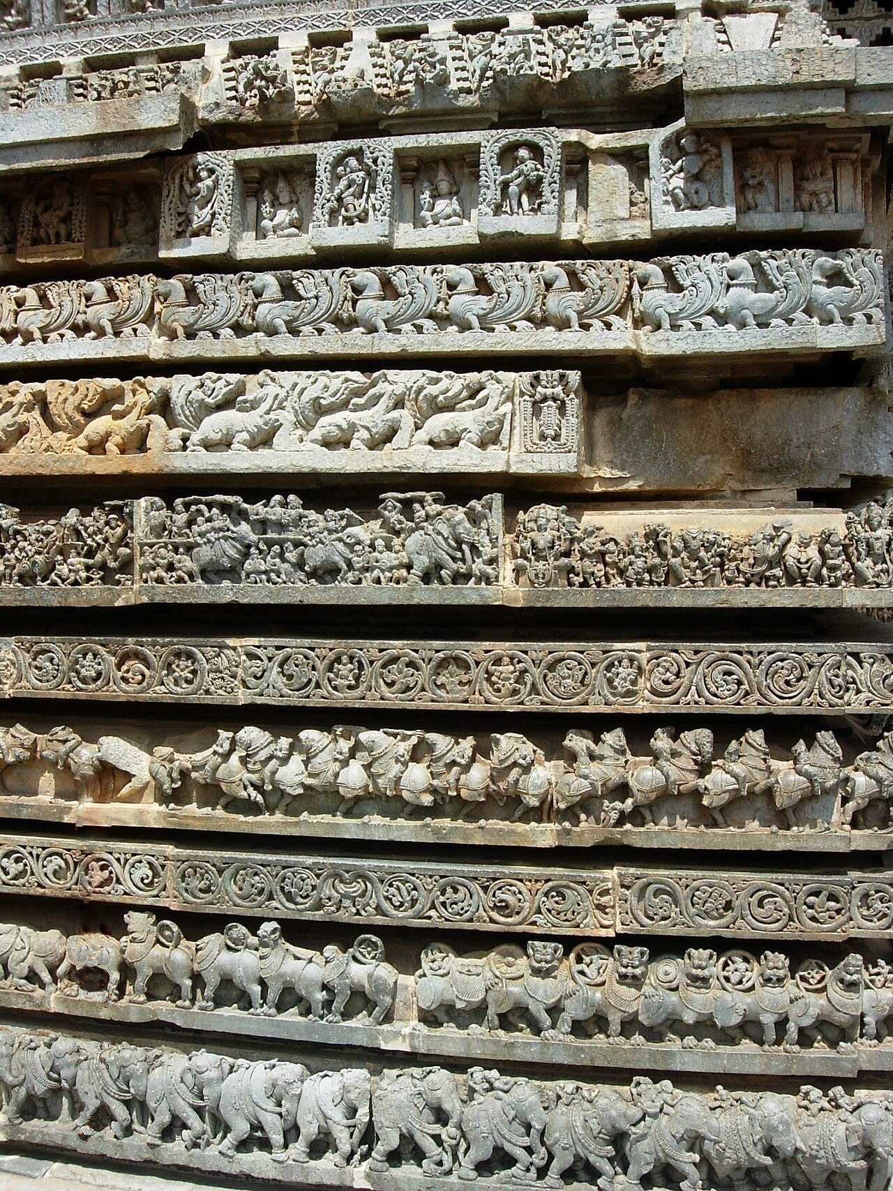 Stacked molding friezes of elephants, lions, scrolls and horsemen circling the outer wall of the Hoysaleswara Temple