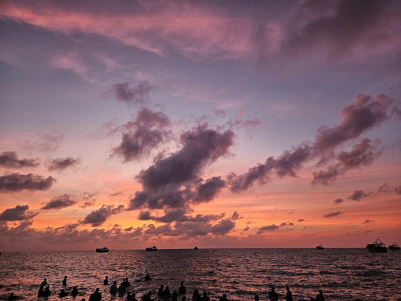 Pilgrims bathing in the sea at Agni Theertham under a dawn sky, Rameswaram