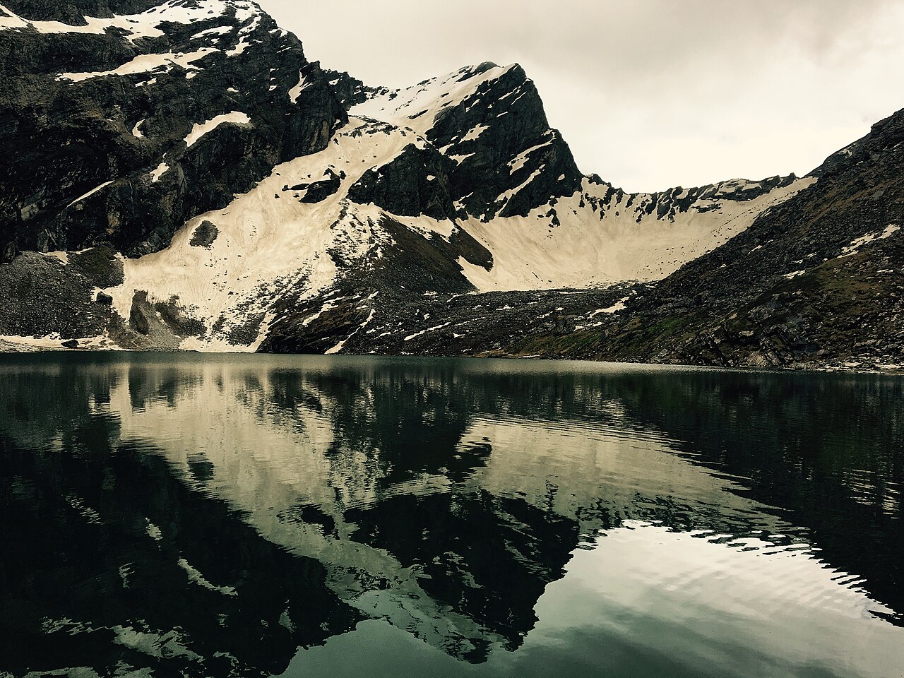 Snow streaked peaks reflected in the still water of the Hemkund sarovar