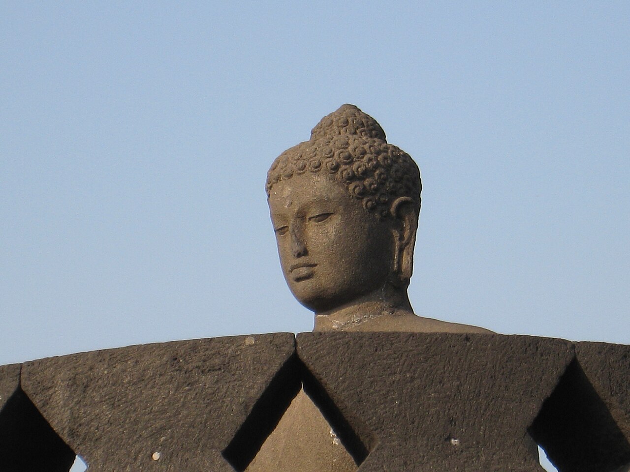 A stone Buddha freed from its latticed stupa gazes out over the Kedu Plain at Borobudur