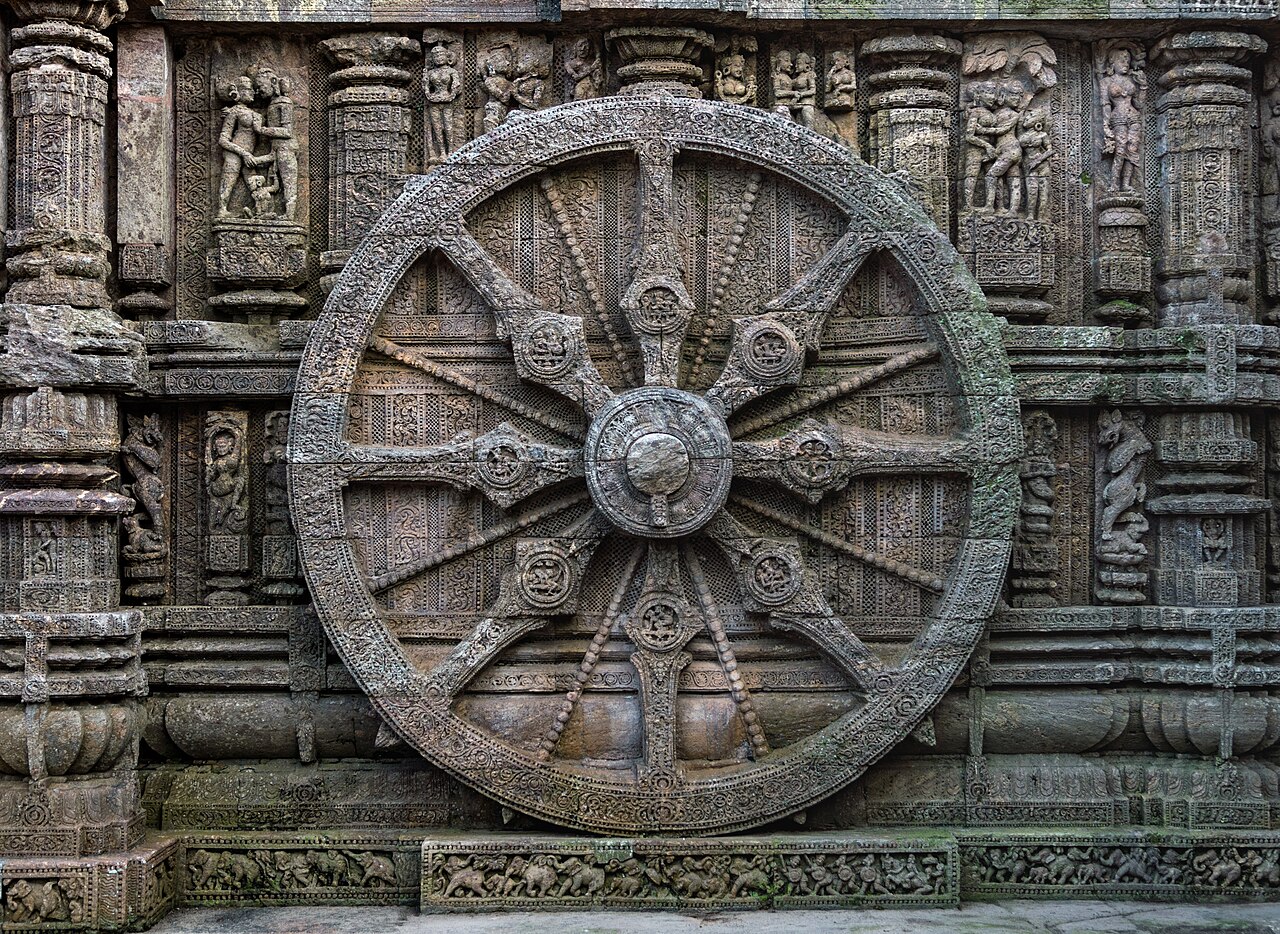 A carved stone chariot wheel of the Konark Sun Temple, its spokes and medallions cut deep into khondalite