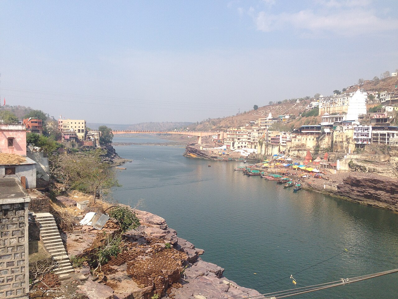The Narmada curving past Mandhata island, the white shikhara of Omkareshwar rising above the ghats with the bridge upstream