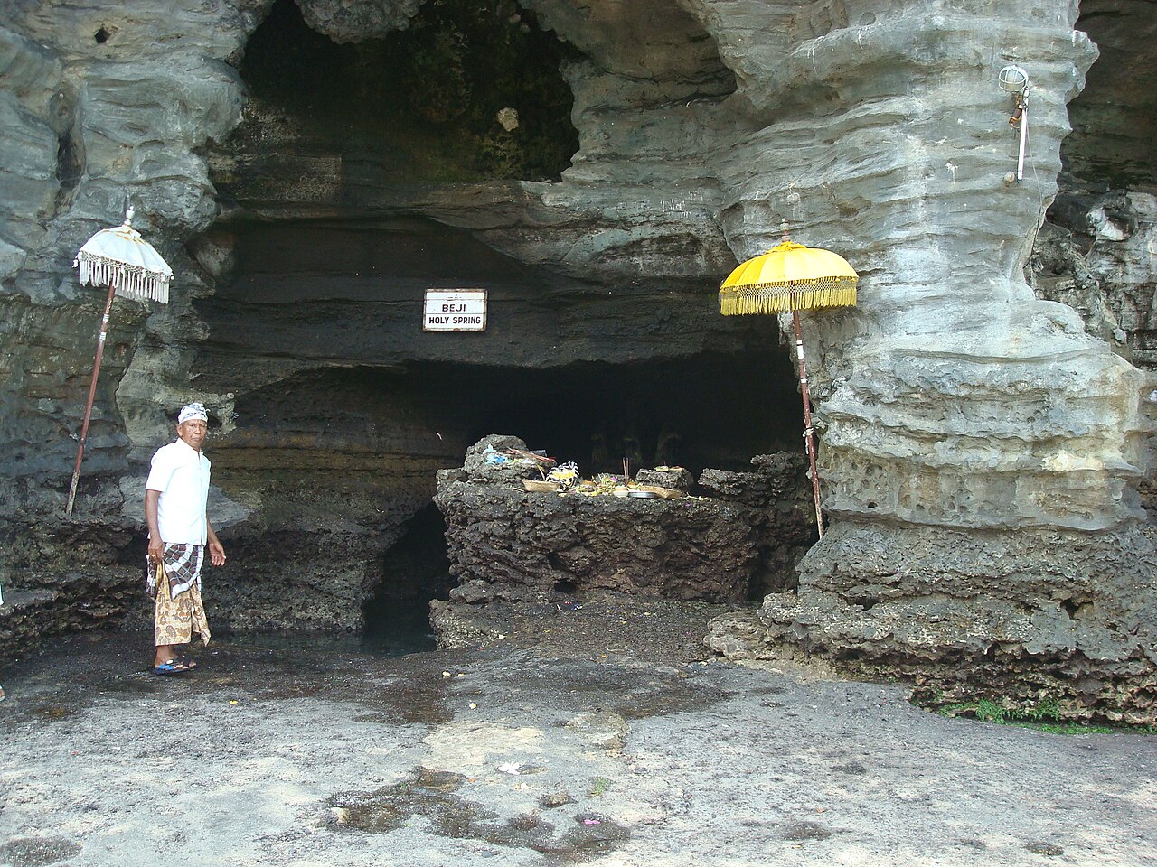 The beji spring in the cave beneath the Tanah Lot rock, sheltered by ceremonial umbrellas