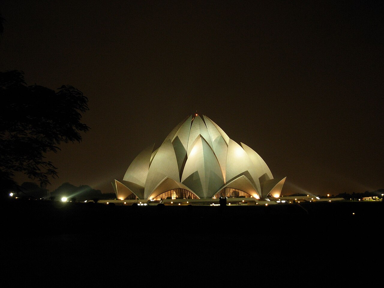 The Bahá'í House of Worship lit from within at night, its petals glowing against the dark