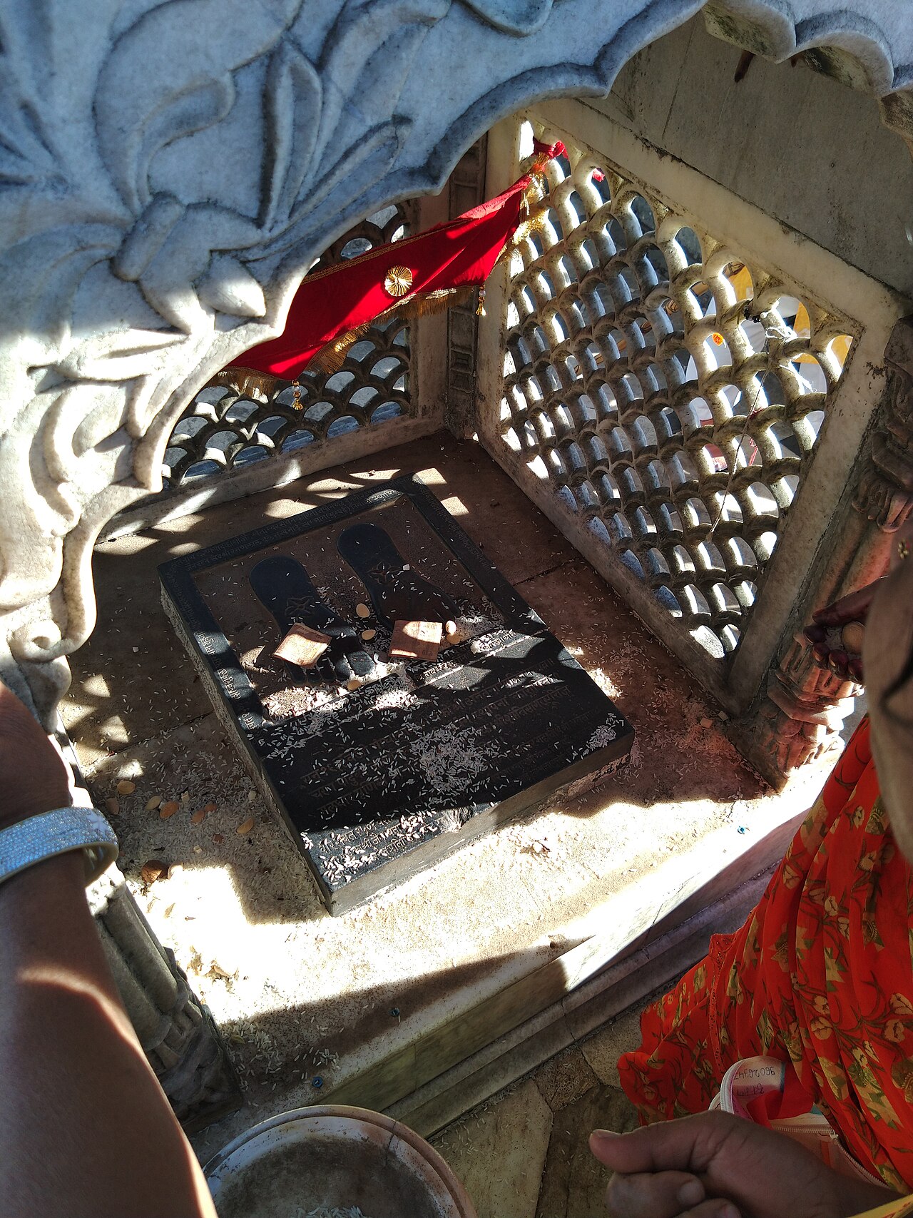 Carved footprints of a Tirthankara strewn with rice offerings inside a tonk on Shikharji