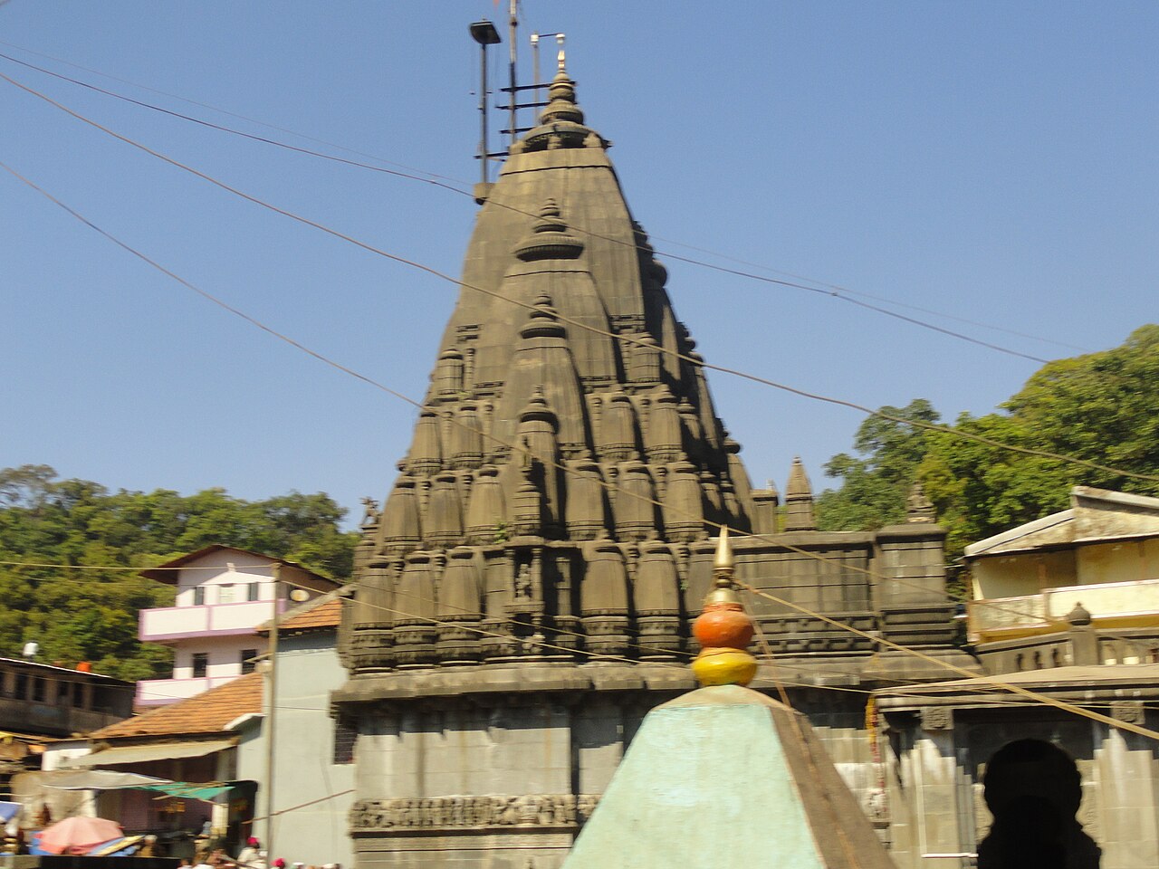 The carved dark stone Nagara shikhara of Shri Bhimashankar Temple against a clear Sahyadri sky