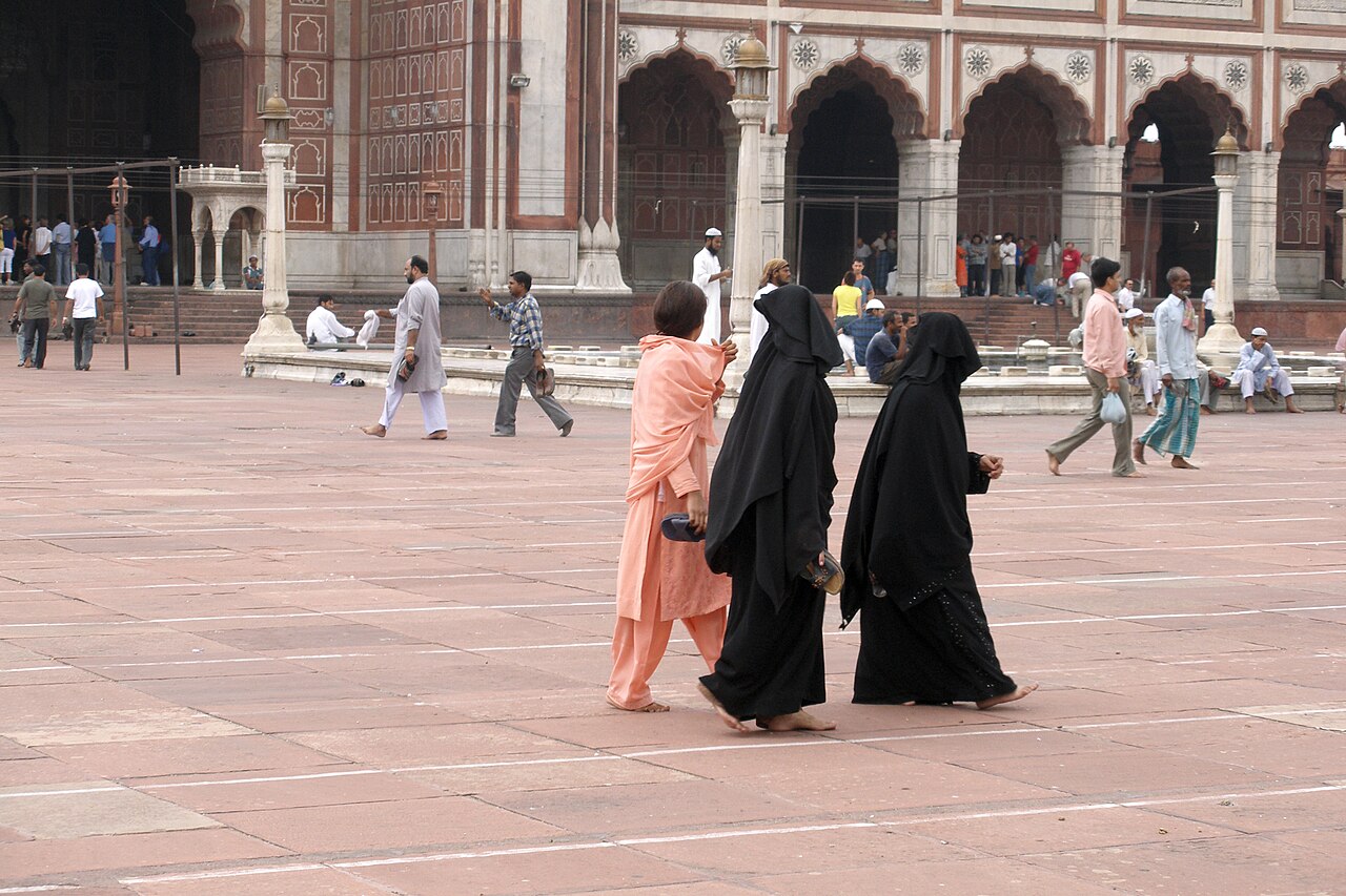 Worshippers crossing the sandstone courtyard of Jama Masjid, Delhi, the prayer hall arcades behind