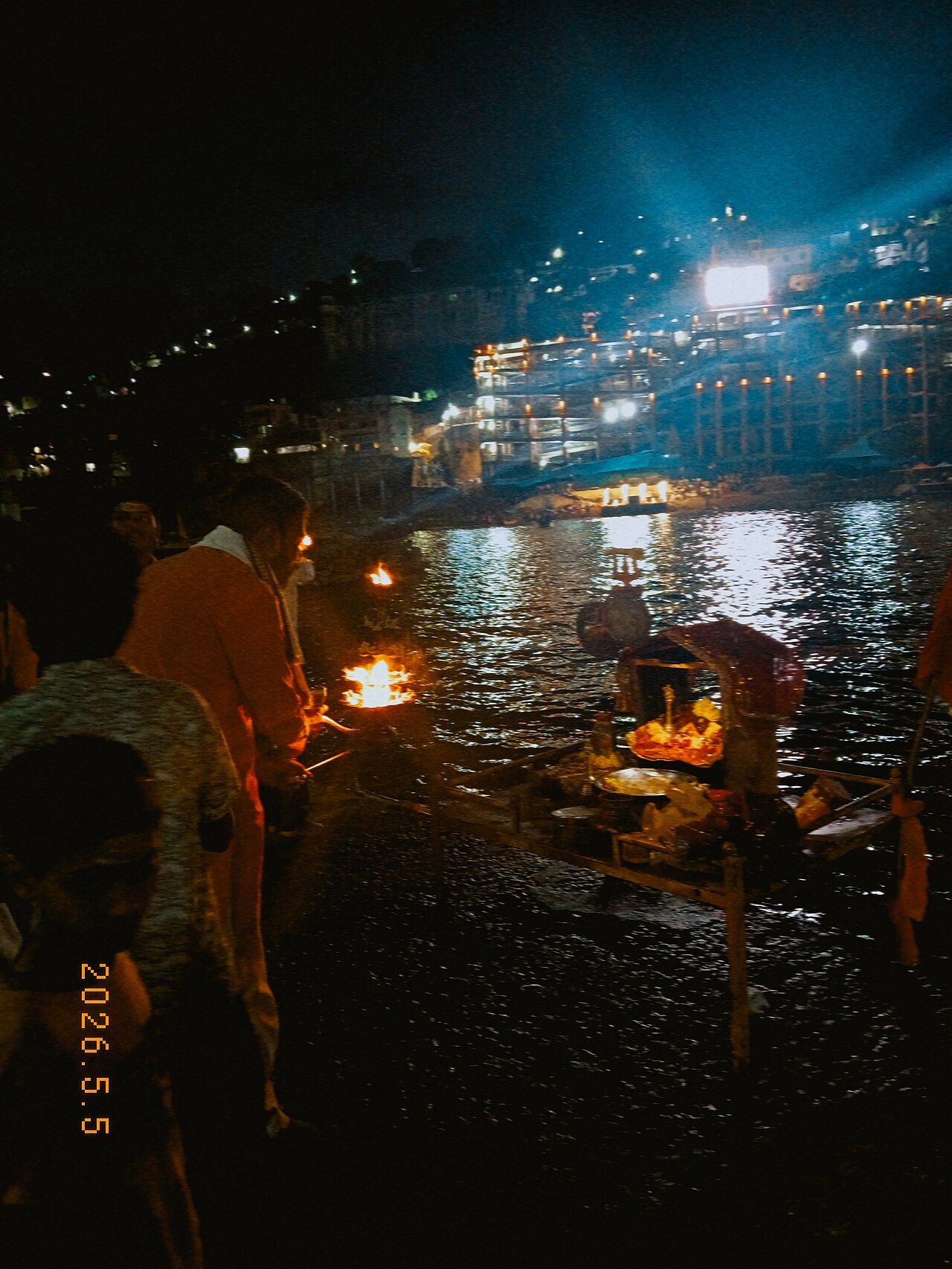 Evening aarti flames at the Narmada ghats in Omkareshwar, the lit island shrine across the dark water