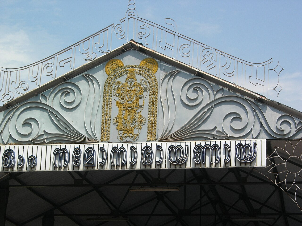 Lord Guruvayurappan worked in gold relief on the east nada gable, above Om Namo Narayanaya in Malayalam script