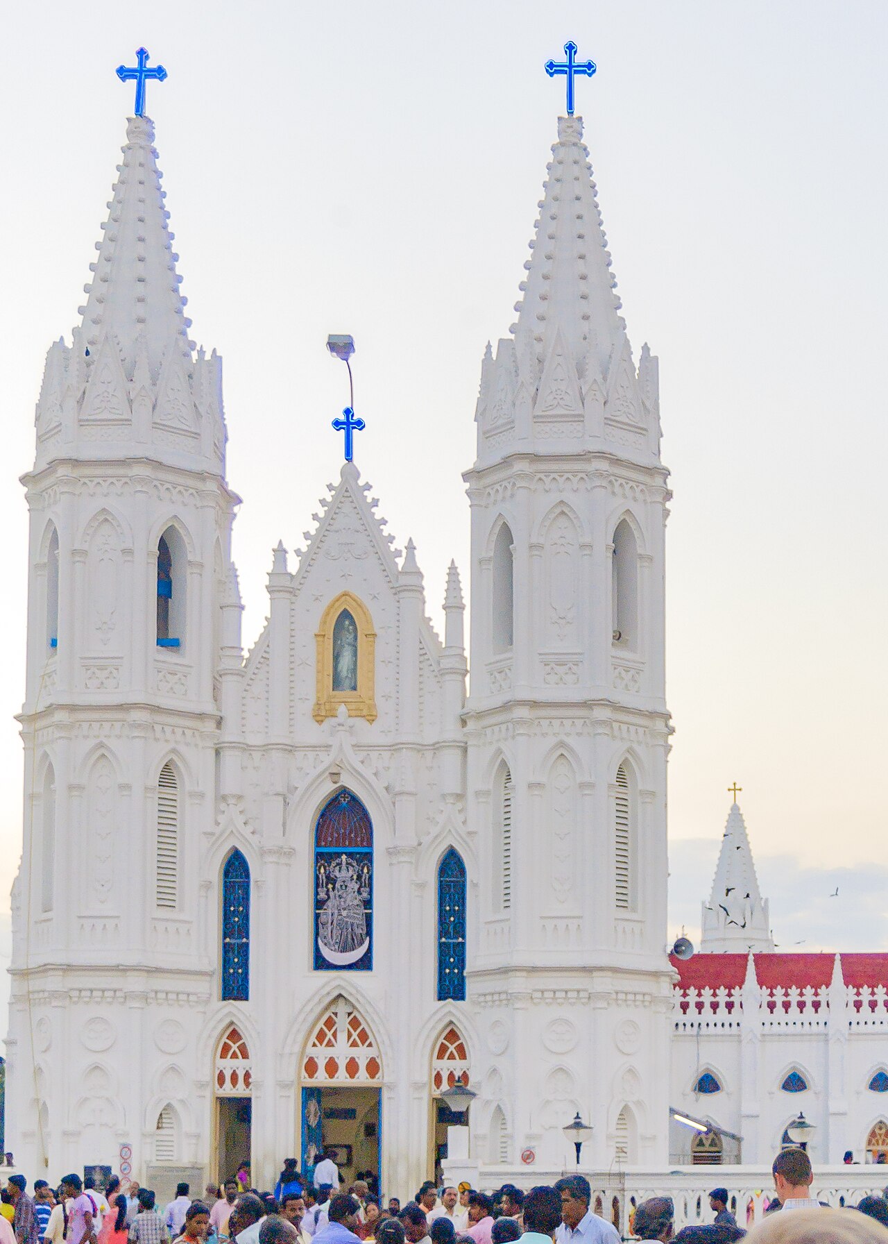 Pilgrims before the white Gothic facade of the basilica, the image of Our Lady of Good Health above the entrance