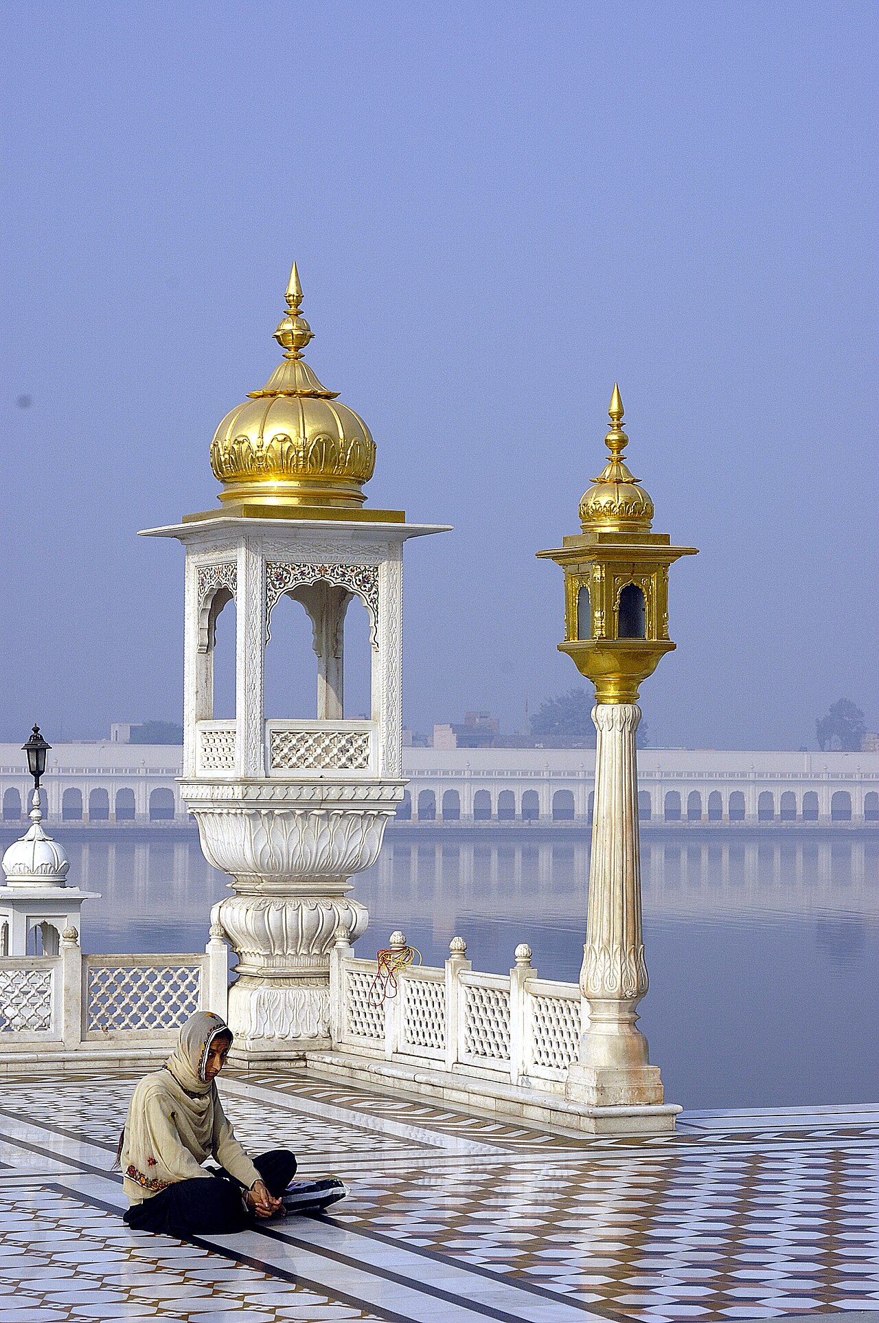 A devotee seated in prayer beside the sarovar at Gurdwara Sri Tarn Taran Sahib